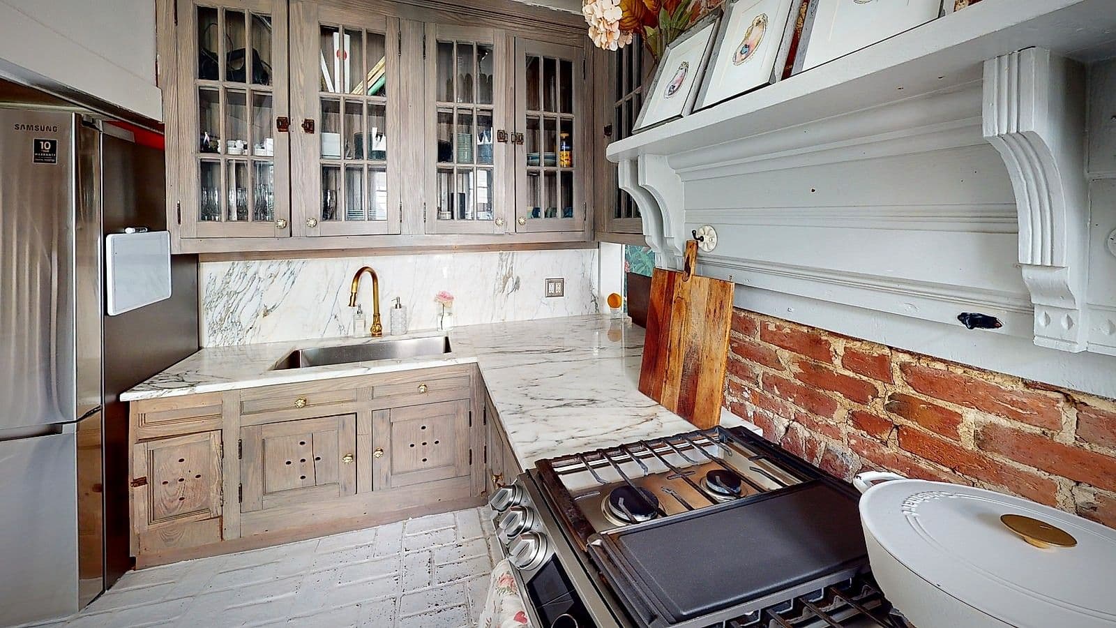 The kitchen at Maison St. LaFleur, with marble counters, brass fixtures, and exposed brick